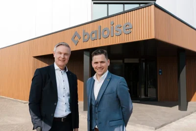 Foto met Arend-Jan Koorn, General Manager Baloise Nederland en Manu Mus, Director Distribution Partnerships Baloise België poserend voor het pand van Baloise in Beesd.