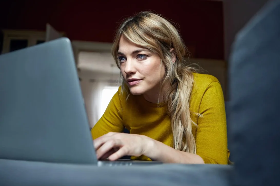 Close up van het gezicht van een jonge vrouw de zeer geconcentreerd op haar laptop aan het werk is.