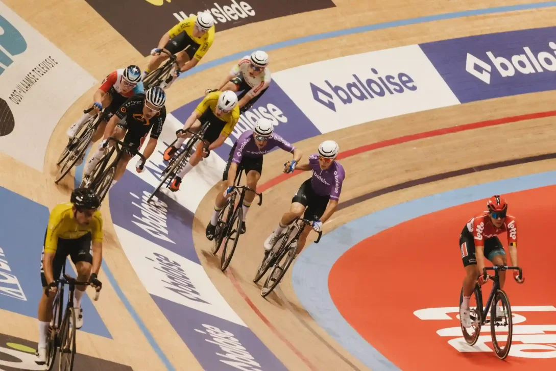Actiefoto van een baanwielrenwedstrijd teamsprint met Baloise-reclame op de baan en o.a. 2 Baloise renners in de race.