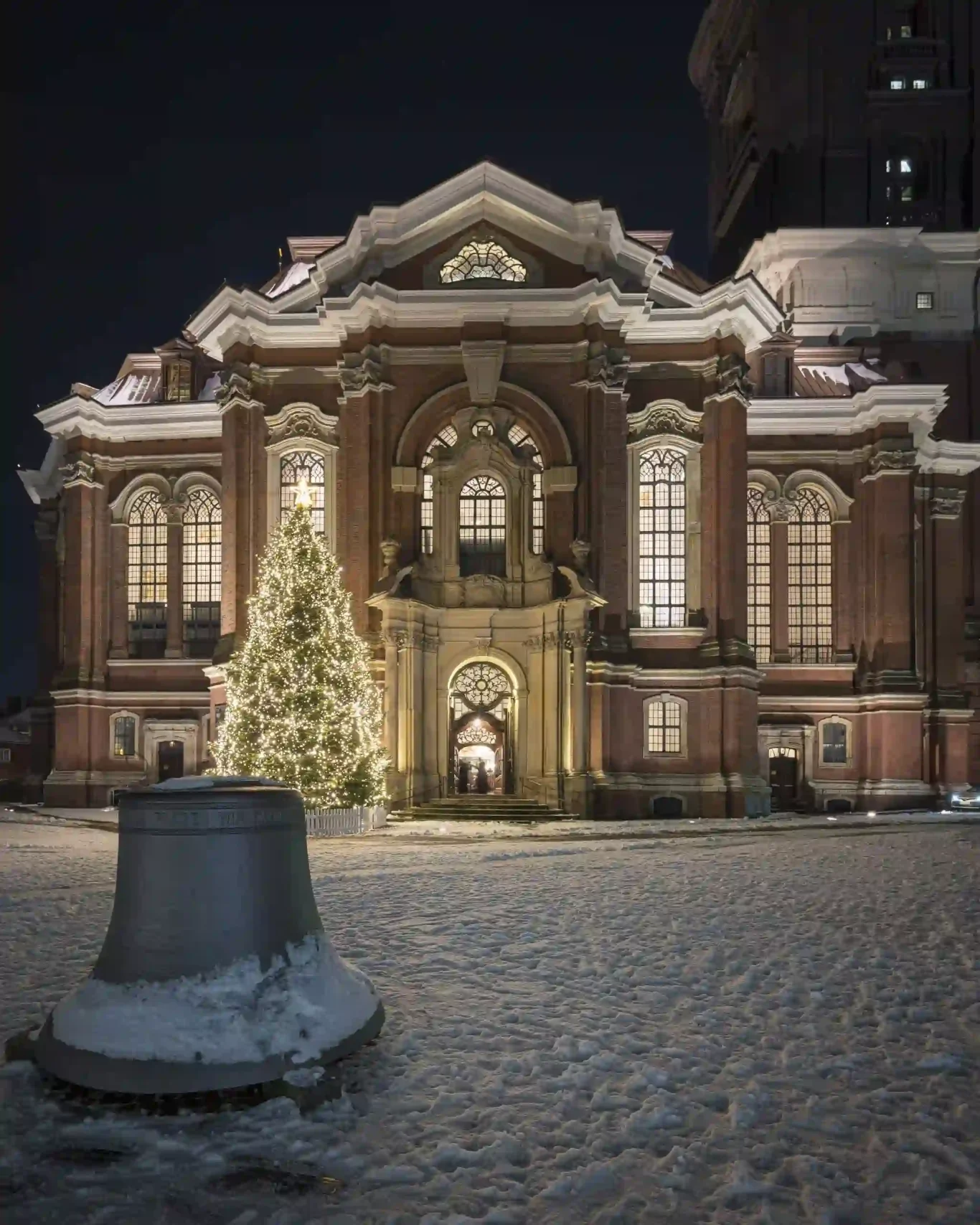 Foto van de verlichte kersboom voor verlichte gevel van de Sint-Michielskerk op een winternacht in Hamburg, Duitsland.