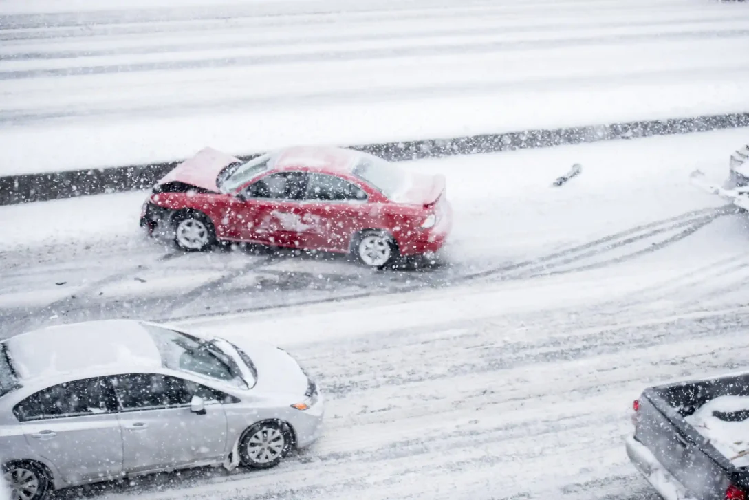 Foto van een rode auto die een ongeluk heeft gehad op de snelweg en is gespind in sneeuw.