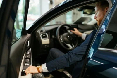 Foto van een man in pak die in zijn auto zit en op het punt staat zijn portier dicht te trekken.